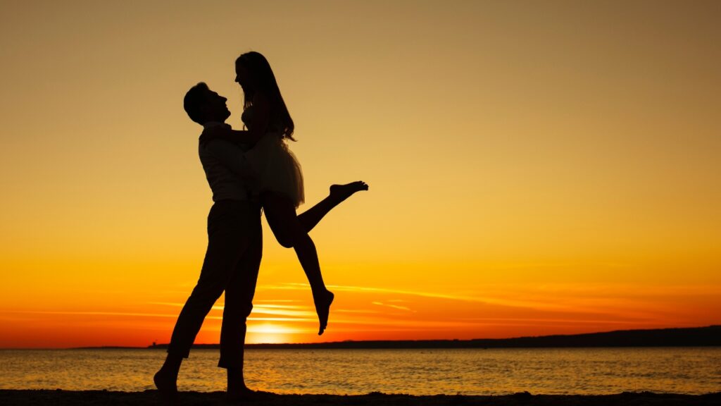 Un hombre y una mujer abrazados en la playa a contraluz mostrando su amor entre ellos