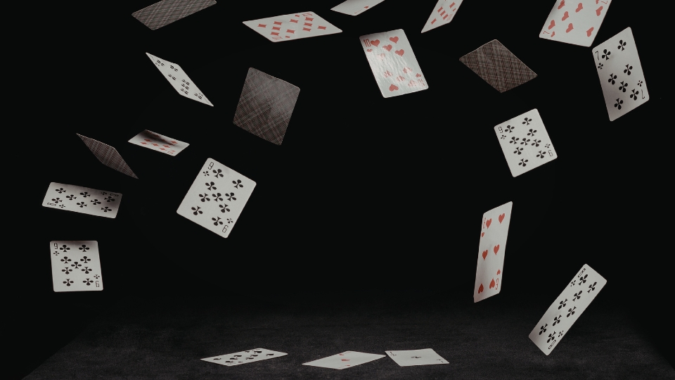 Baraja de cartas cayendo desordenada sobre un fondo negro 