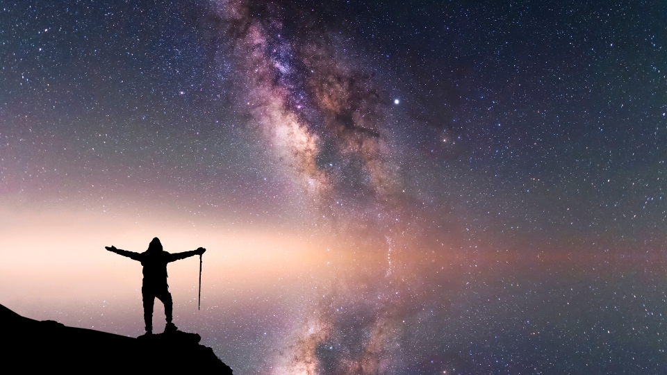 Una persona en lo alto de una montaña observando el espacio con el cielo despejado